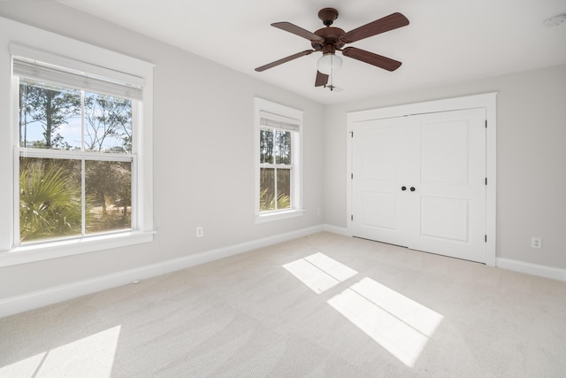 unfurnished bedroom with light carpet, multiple windows, and baseboards