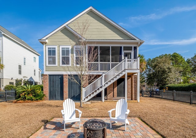 rear view of property featuring a patio area, stairway, fence, and a sunroom