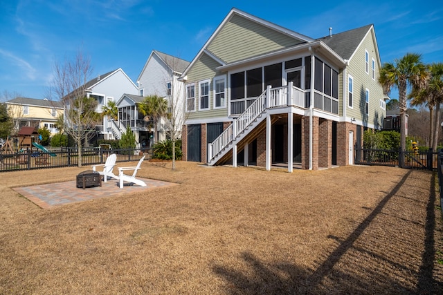 back of property with fence, an outdoor fire pit, stairway, a sunroom, and a patio area