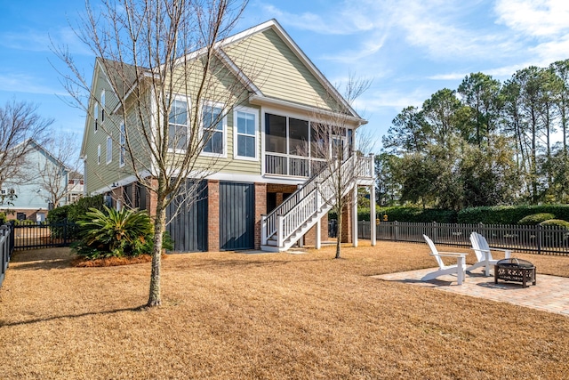 rear view of house featuring a fire pit, fence, stairs, a sunroom, and a patio area