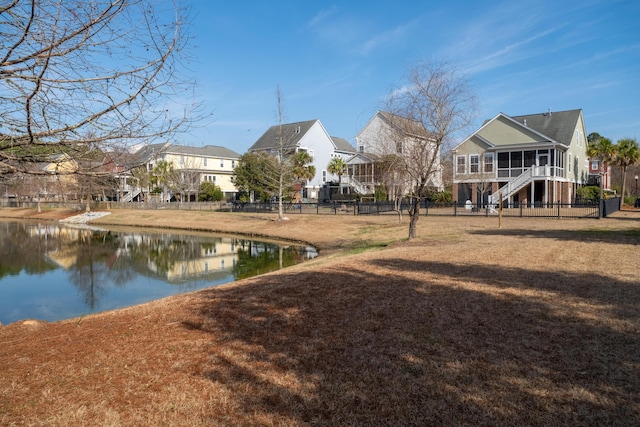 exterior space with a water view, fence, a residential view, stairs, and a yard