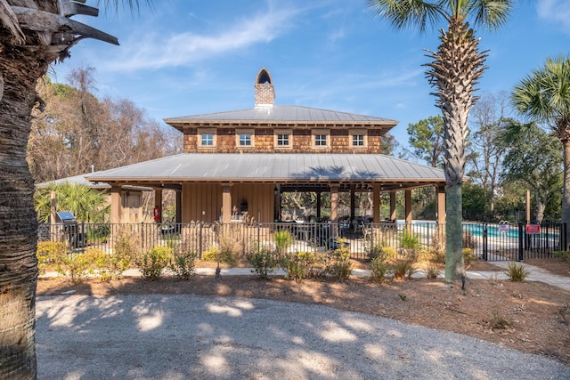 view of front of home with metal roof, a patio area, a chimney, and fence