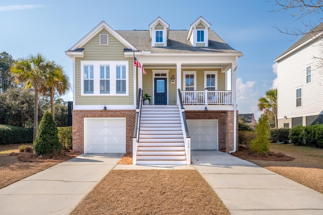 coastal home featuring stairs, a porch, concrete driveway, and an attached garage