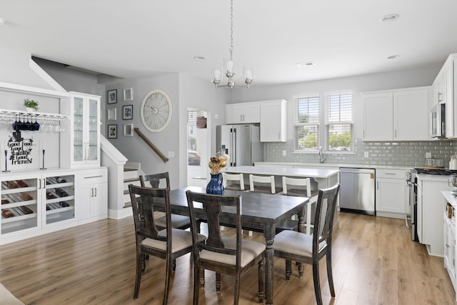 dining room featuring light wood-style flooring, a chandelier, recessed lighting, and stairs