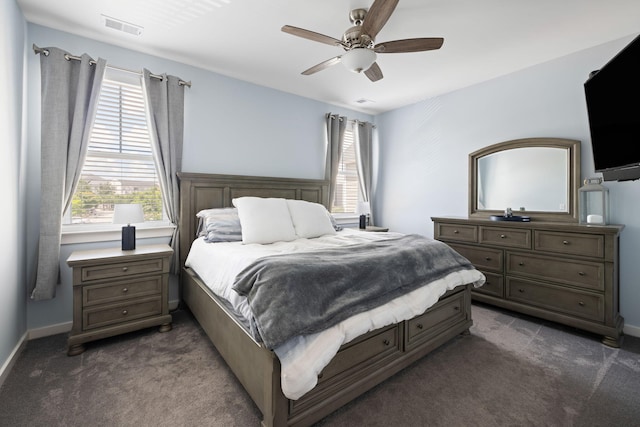 bedroom featuring dark colored carpet, multiple windows, a ceiling fan, and baseboards