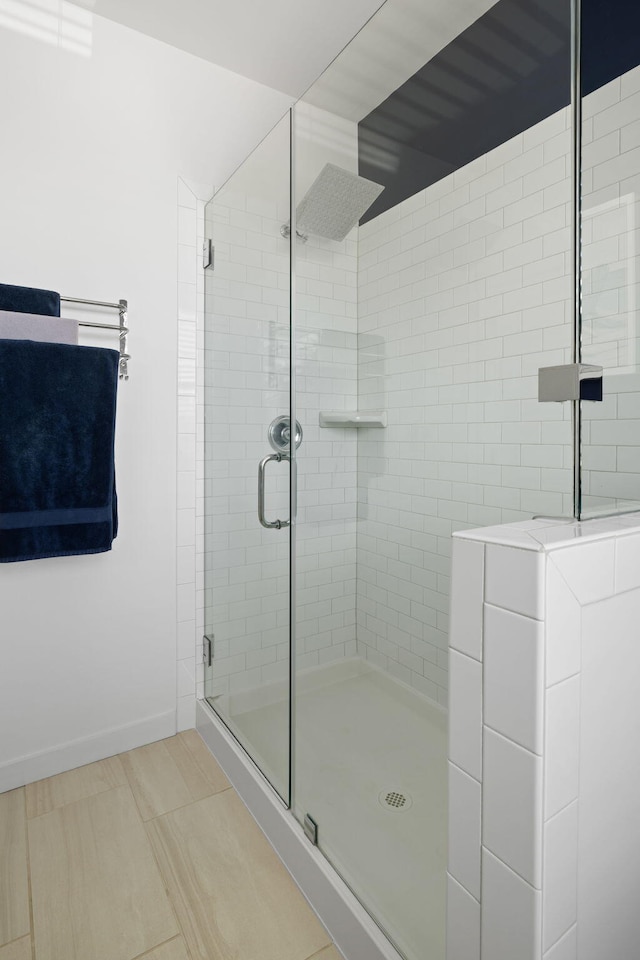 full bath with a shower stall, baseboards, and tile patterned flooring