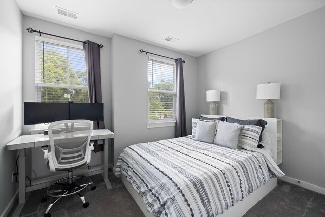 carpeted bedroom featuring multiple windows, baseboards, and an office area