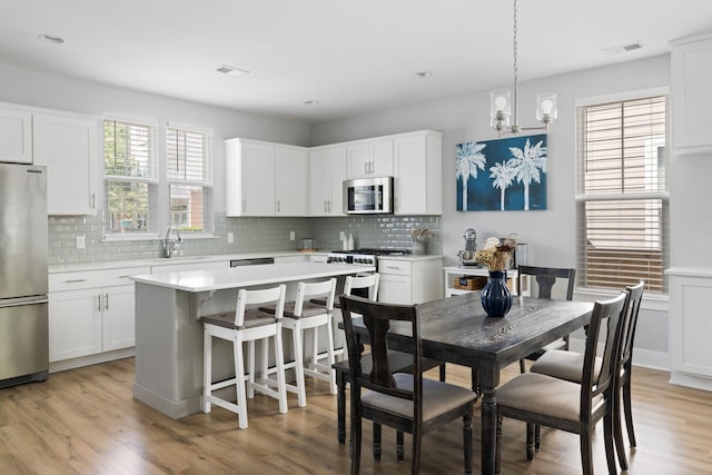 kitchen featuring stainless steel appliances, a sink, light countertops, decorative backsplash, and recessed lighting