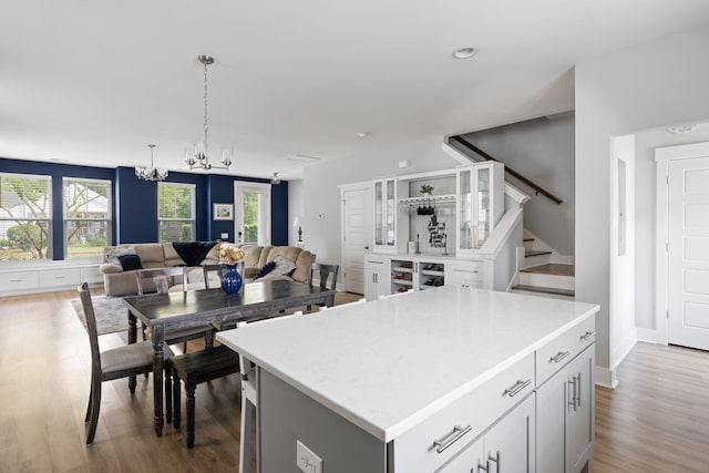 kitchen featuring a chandelier, open floor plan, wood finished floors, a kitchen island, and light countertops