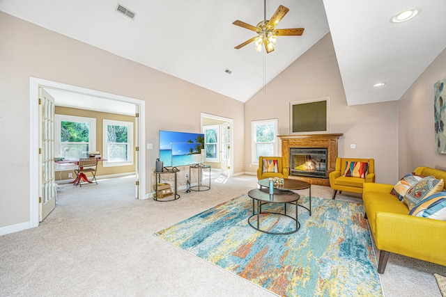 carpeted living room with ceiling fan, plenty of natural light, and high vaulted ceiling