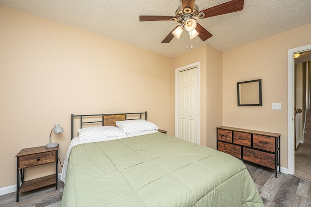 bedroom with ceiling fan, a textured ceiling, and dark wood-type flooring