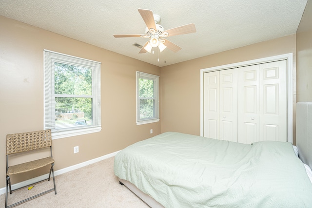 carpeted bedroom featuring ceiling fan, a closet, and a textured ceiling