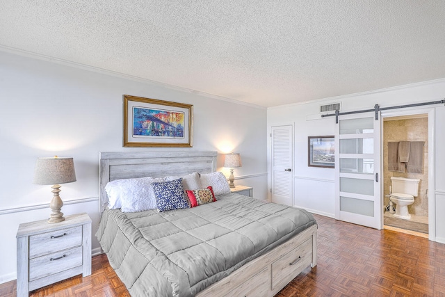 bedroom featuring dark parquet floors, a textured ceiling, a barn door, crown molding, and ensuite bathroom