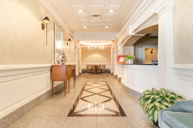 corridor featuring coffered ceiling, ornamental molding, an inviting chandelier, and ornate columns