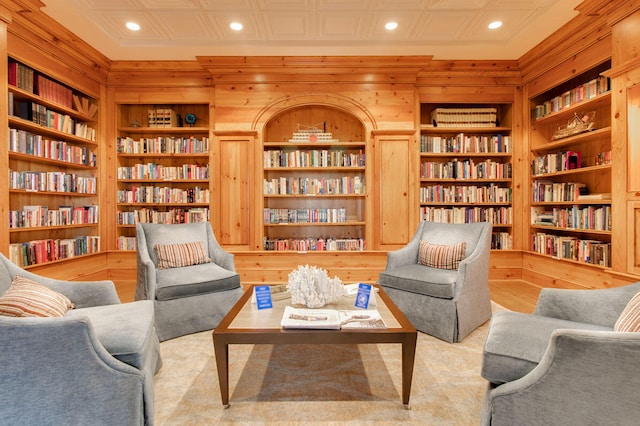 living area with light wood-type flooring, built in shelves, and wood walls