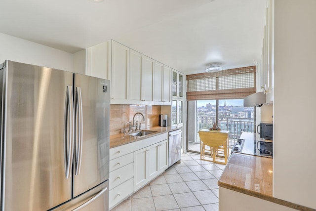 kitchen featuring appliances with stainless steel finishes, white cabinetry, light stone counters, tasteful backsplash, and sink