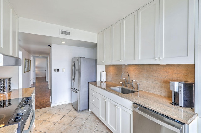 kitchen featuring light stone counters, light tile patterned flooring, sink, white cabinets, and appliances with stainless steel finishes