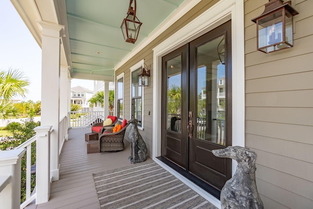 view of exterior entry with covered porch and french doors