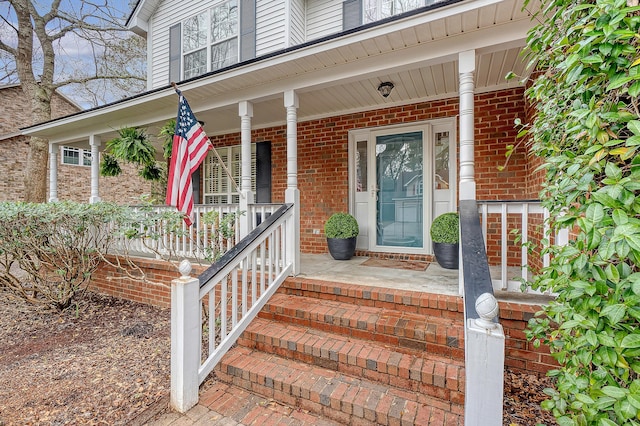 view of exterior entry with covered porch and brick siding