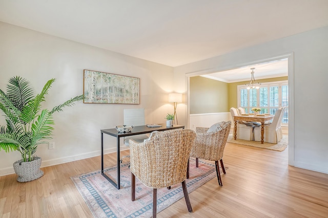 office space with baseboards, light wood-type flooring, a notable chandelier, and ornamental molding