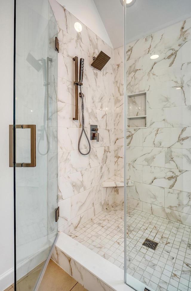 full bathroom with a marble finish shower and vaulted ceiling