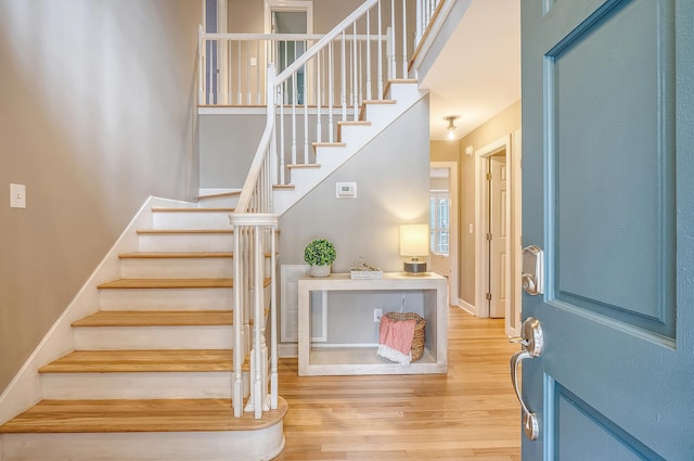 entryway with baseboards, visible vents, wood finished floors, and stairway
