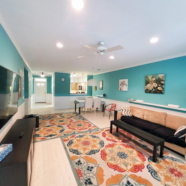 living room featuring hardwood / wood-style floors, ceiling fan, and crown molding