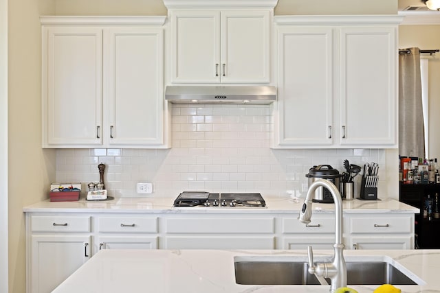 kitchen with light stone counters, backsplash, and white cabinets