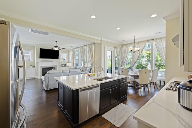 kitchen featuring a center island with sink, appliances with stainless steel finishes, ornamental molding, pendant lighting, and sink