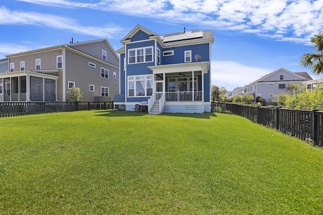 back of house featuring a lawn, solar panels, and a sunroom