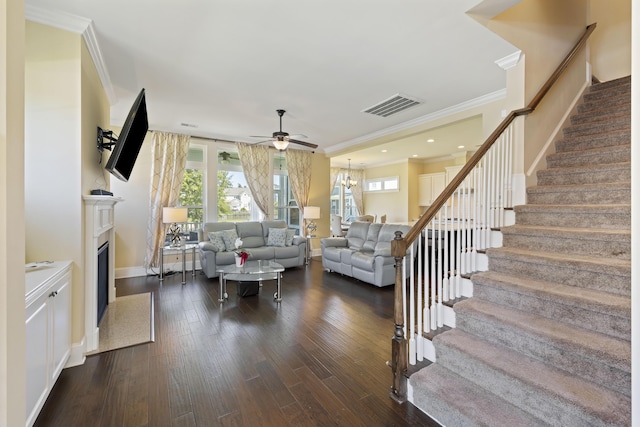 living room with ceiling fan with notable chandelier, dark hardwood / wood-style flooring, and ornamental molding