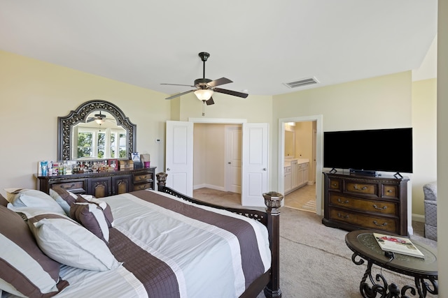 bedroom featuring ceiling fan, light colored carpet, and ensuite bathroom