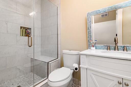 bathroom featuring toilet, a shower with door, and vanity