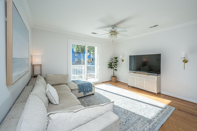living room with crown molding, ceiling fan, light wood-style floors, and baseboards