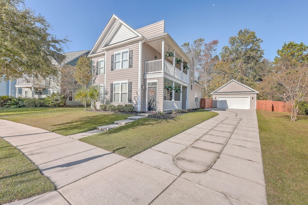 view of front of home featuring a front lawn, a balcony, an outbuilding, and a garage