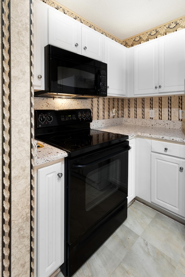 kitchen featuring a textured ceiling, black appliances, white cabinetry, and light stone counters