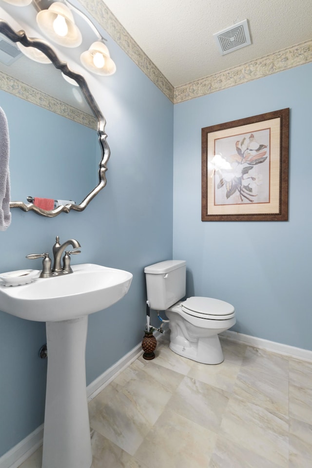 bathroom with a textured ceiling, sink, and toilet