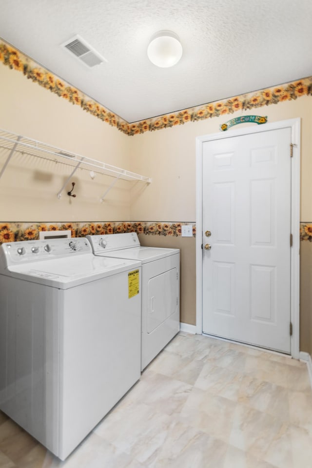 laundry room with a textured ceiling and independent washer and dryer