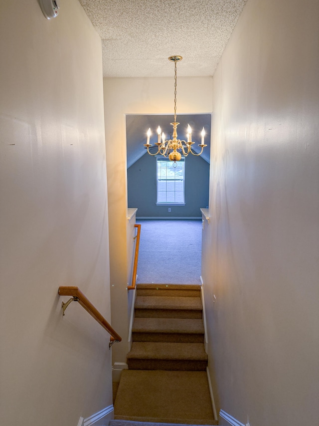 stairs with a textured ceiling, a chandelier, vaulted ceiling, and carpet