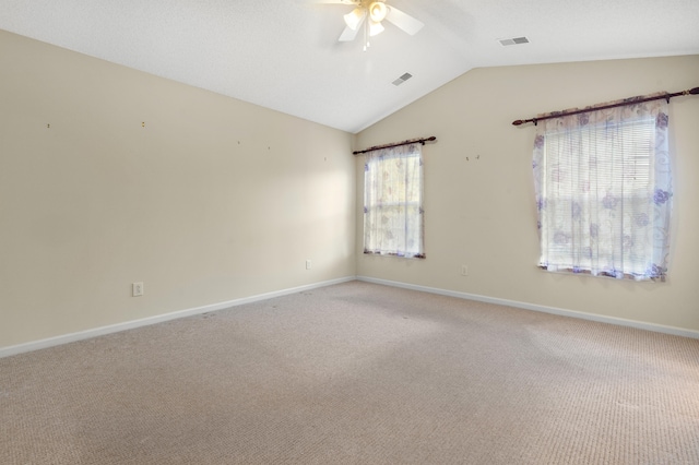 unfurnished room with lofted ceiling, plenty of natural light, and carpet flooring