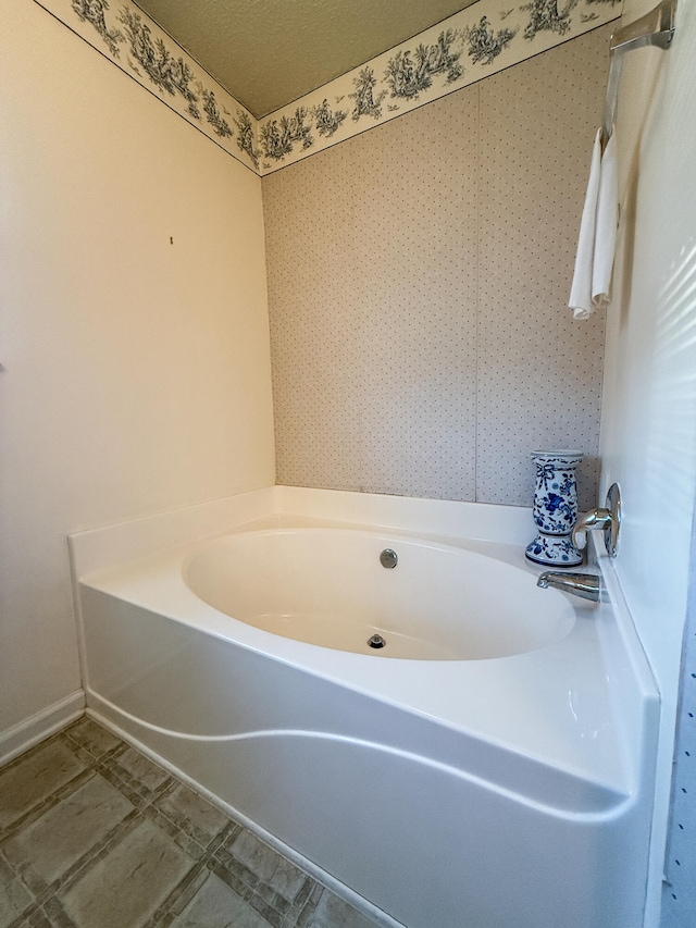 bathroom with a textured ceiling and a bathtub