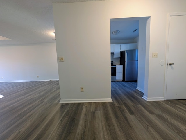 empty room with dark hardwood / wood-style flooring and a textured ceiling