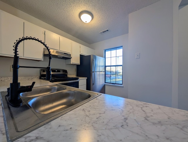 kitchen featuring a textured ceiling, stainless steel appliances, and white cabinetry