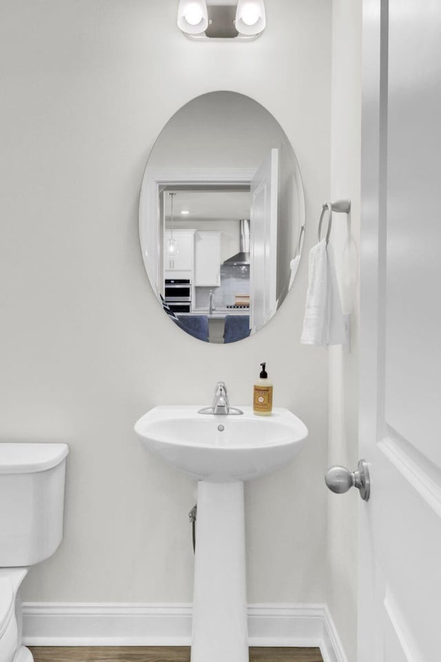 bathroom featuring toilet, wood finished floors, and baseboards