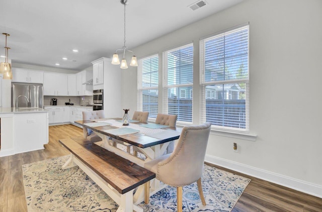 dining area featuring light wood finished floors, visible vents, a chandelier, and baseboards