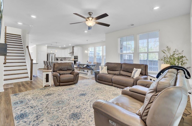 living area featuring visible vents, a ceiling fan, wood finished floors, recessed lighting, and stairway