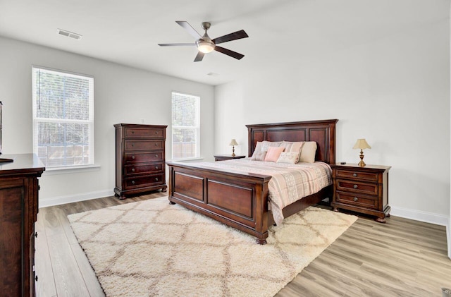 bedroom with a ceiling fan, baseboards, visible vents, and light wood finished floors