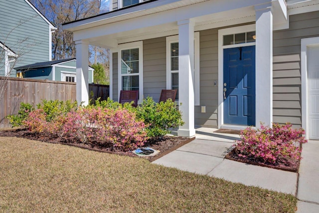 entrance to property with a porch and fence