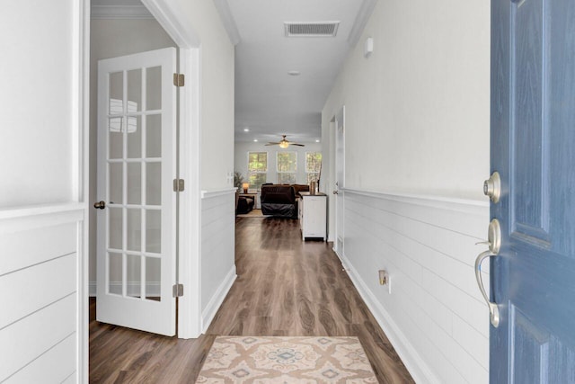 corridor featuring visible vents, dark wood-type flooring, and a wainscoted wall