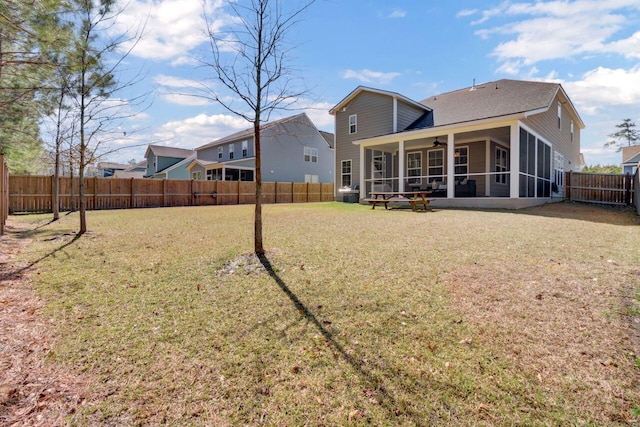 rear view of house with a ceiling fan, a lawn, a fenced backyard, and a sunroom